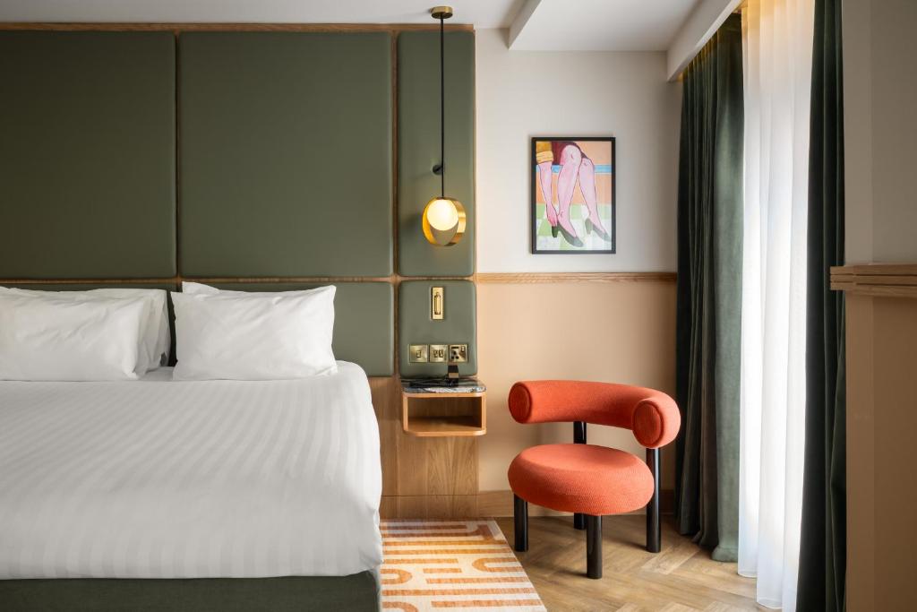 a bedroom with a bed and a red chair at Carlton George Hotel in Glasgow