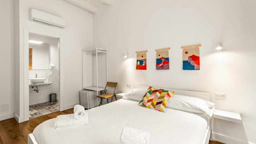 a white bedroom with a white bed and a sink at Ceramic Rooms in Oristano