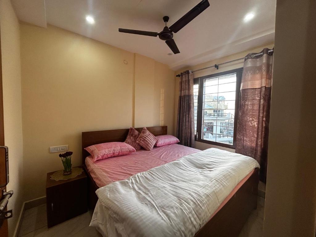 a bedroom with a bed with pink sheets and a window at Uttarayan The Homestay in Almora