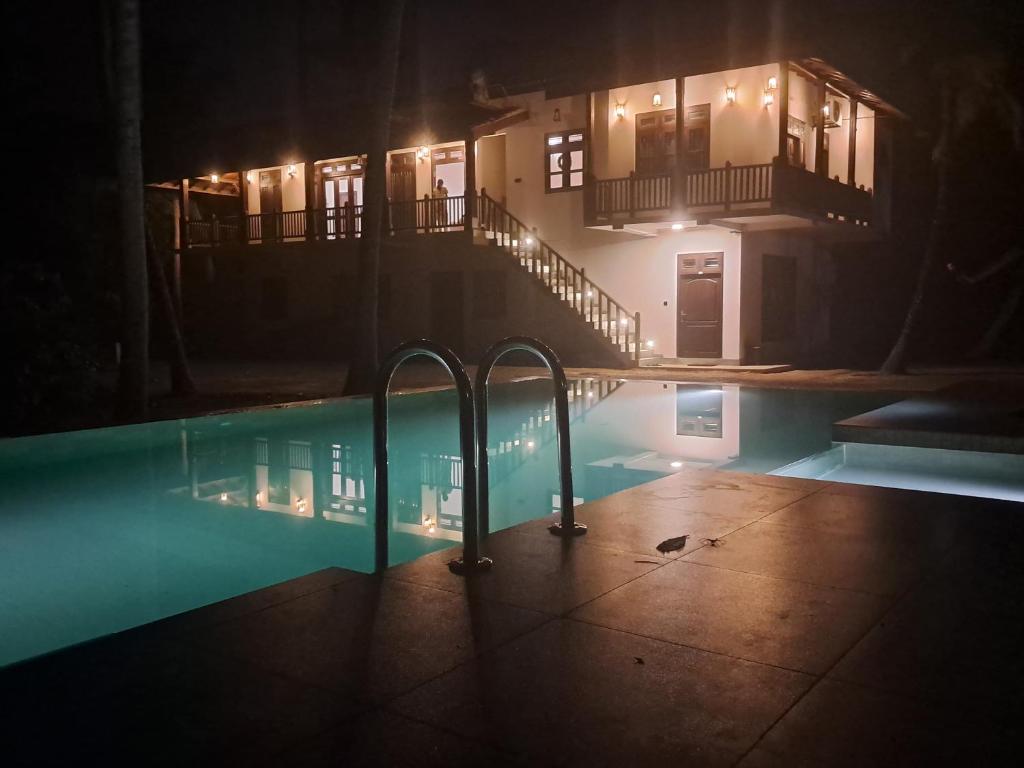 a swimming pool at night with a house in the background at Cinnamon Lagoon Villas in Unawatuna
