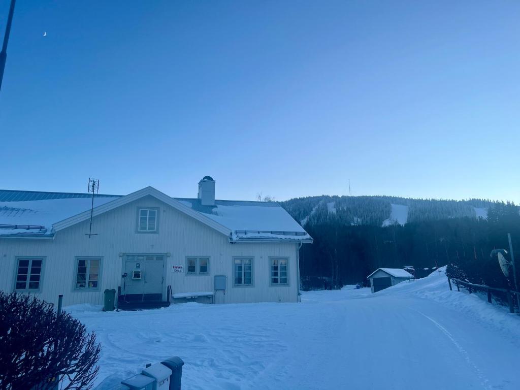 a white house with snow on the ground at Huså byskola in Järpen