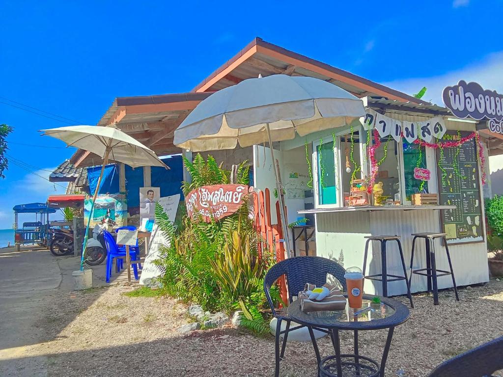 a building with a table and chairs and an umbrella at Yada homestay in Ban Bu Lu