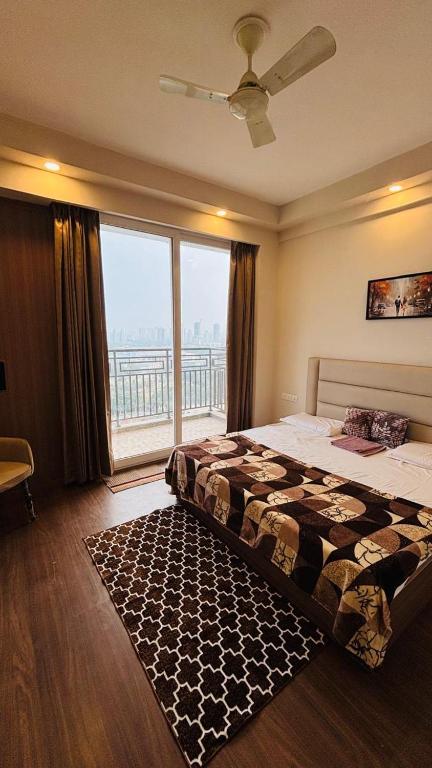 a bedroom with a bed and a large window at Skybloom stays in Greater Noida