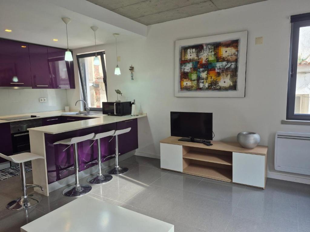 a kitchen with purple and white cabinets and a tv at 123 Muda Life in Sesimbra