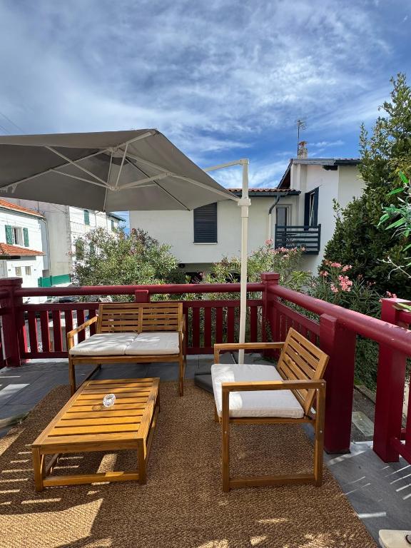 a patio with two benches and an umbrella at Studio Biarritz Côte des Basques in Biarritz