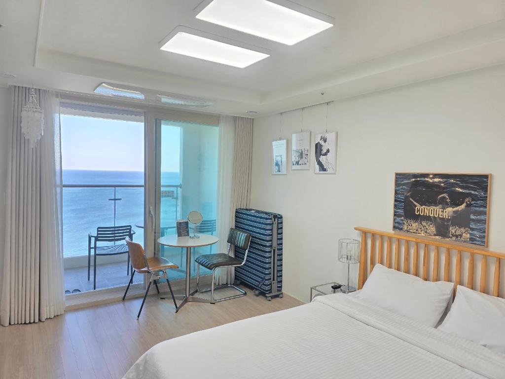 a bedroom with a bed and a table with chairs at Sokcho Summitbay 1708 "Panoramic Ocean View" in Sokcho