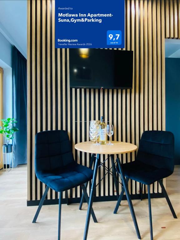 a table with two chairs and a tv on a wall at Motlawa Inn Apartment-Suna,Gym&Parking in Gdańsk