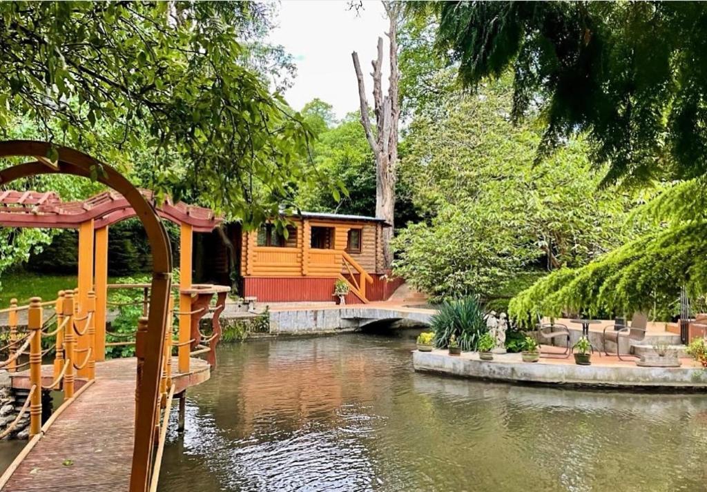 a cabin in the middle of a pond in a garden at Traditional Log Cabin next to Harry Potter Studios in Kings Langley