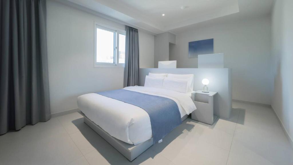 a white bedroom with a large bed and a window at The M Hotel in Seoul