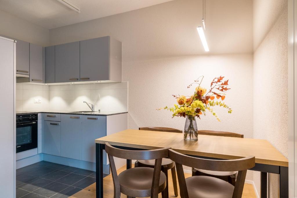 a kitchen with a wooden table with chairs and a vase of flowers at Apartment Harderstrasse in Interlaken