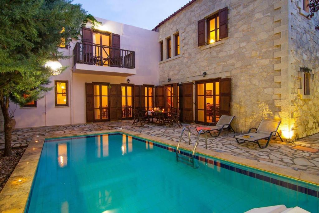 a swimming pool in front of a house at Sarris Villa in Áyios Mámas