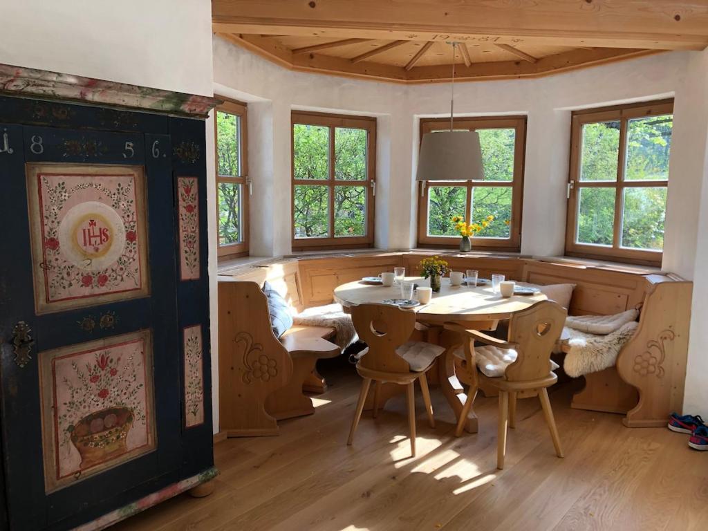 a dining room with a table and chairs and windows at Bergblick Kampenwand in Aschau im Chiemgau