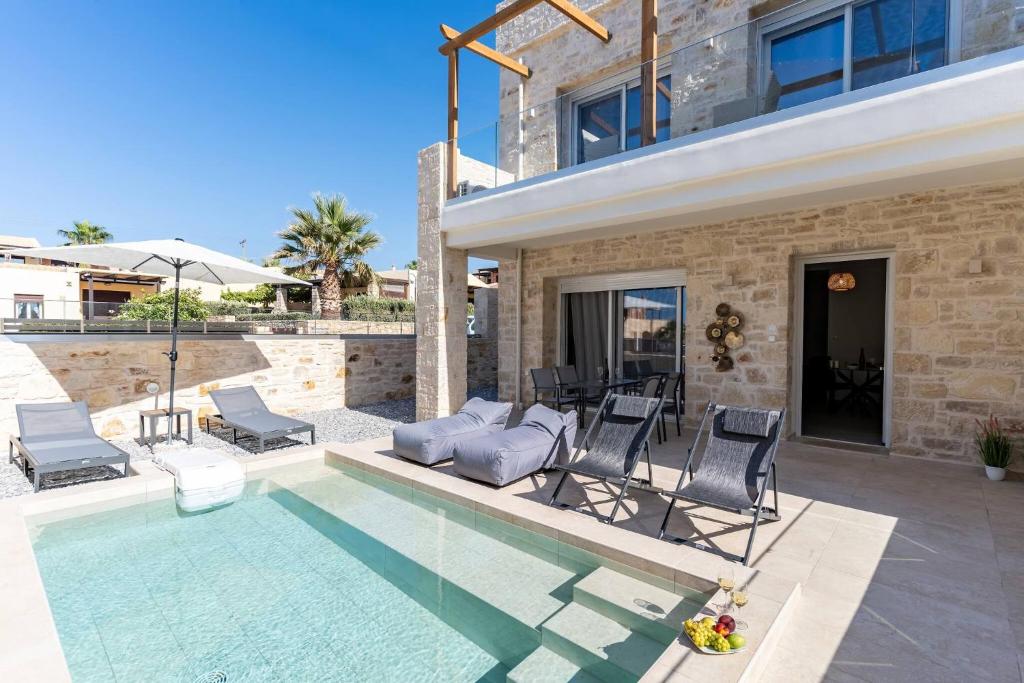 a villa with a swimming pool and chairs and a house at Symphony Suite in Panormos Rethymno