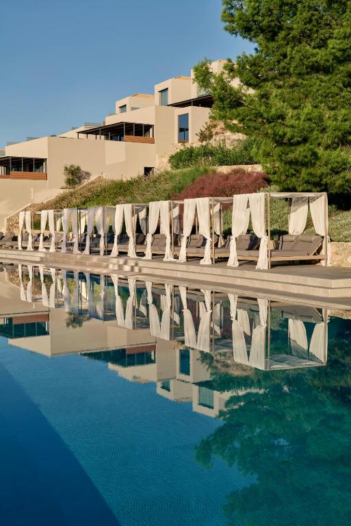a row of lounge chairs and a pool of water at Celestial All Suites in Kefallonia