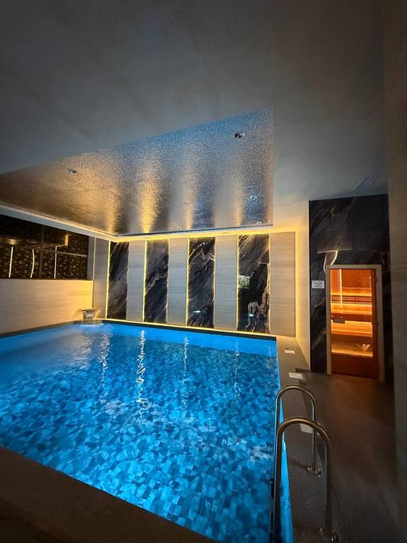 a large swimming pool with blue water in a room at Fidji Hotel in Yerevan