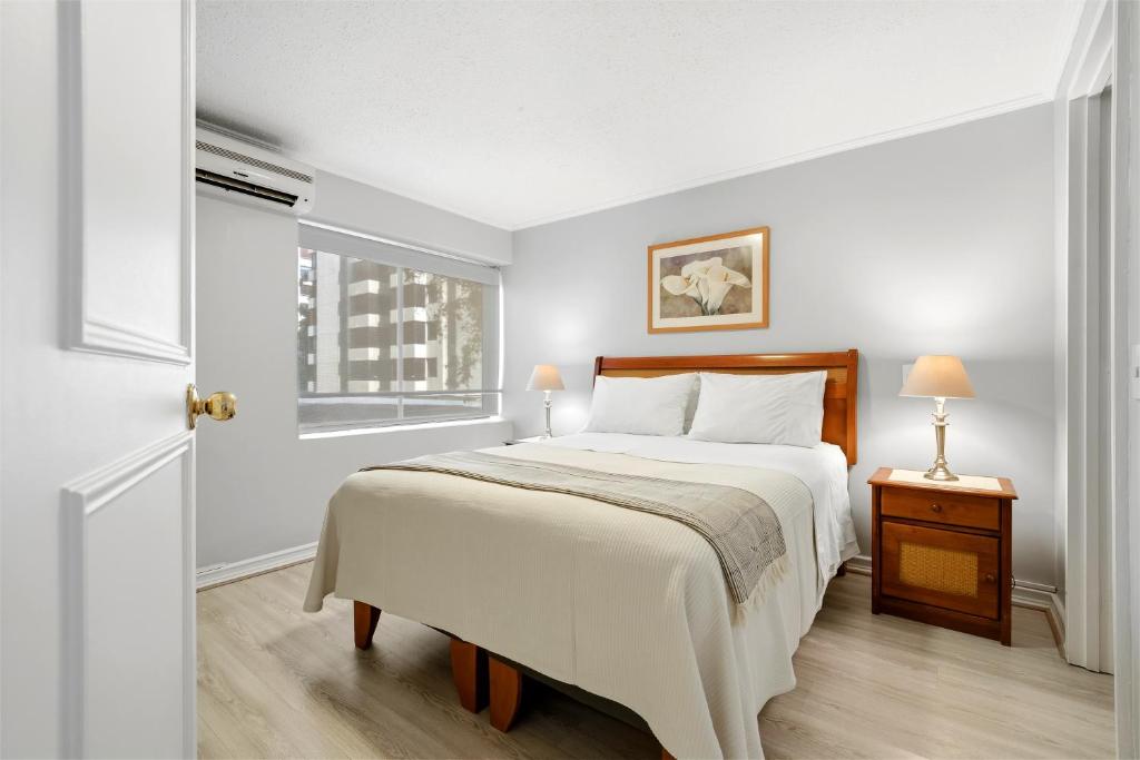 a white bedroom with a bed and a window at Isabel Suites Vitacura in Santiago