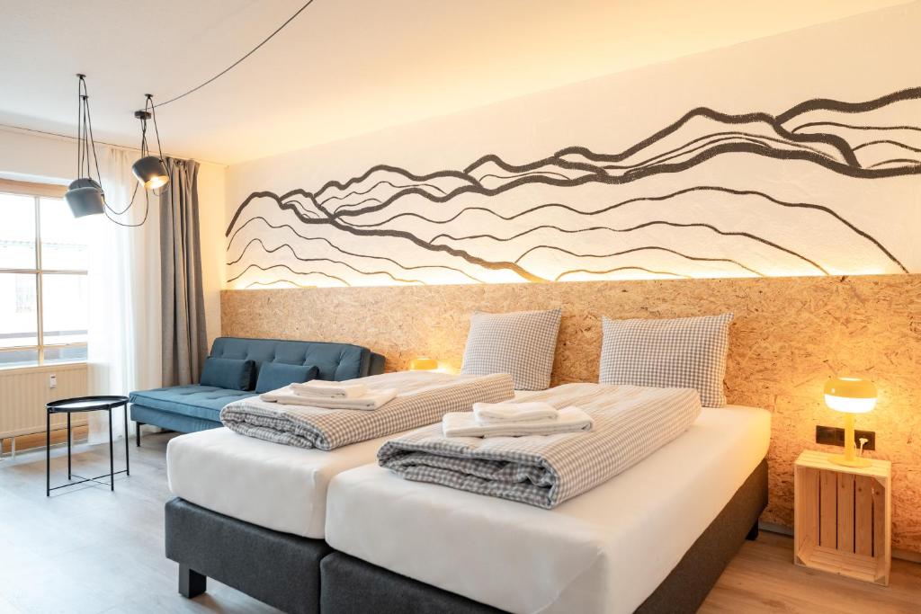 two beds in a room with a mural on the wall at Weitnau Stays - Hotel & Hostel in Weitnau
