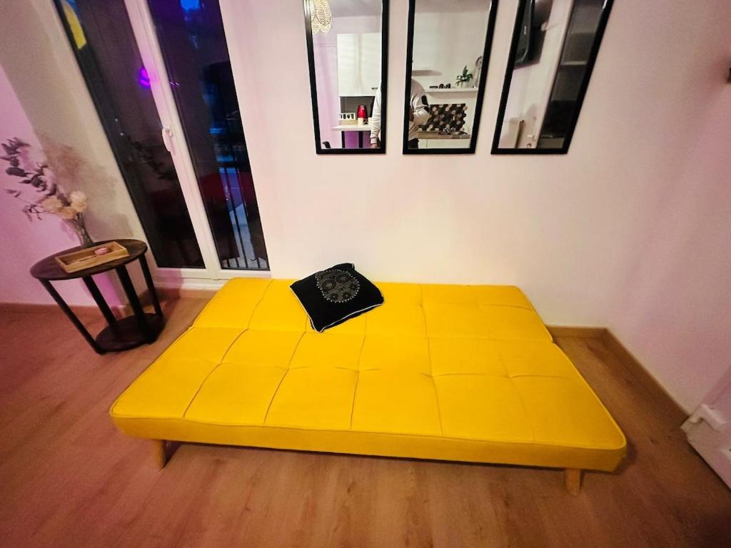 a yellow bed in a room with a table at petit studio de bourgogne in Saint-Albain