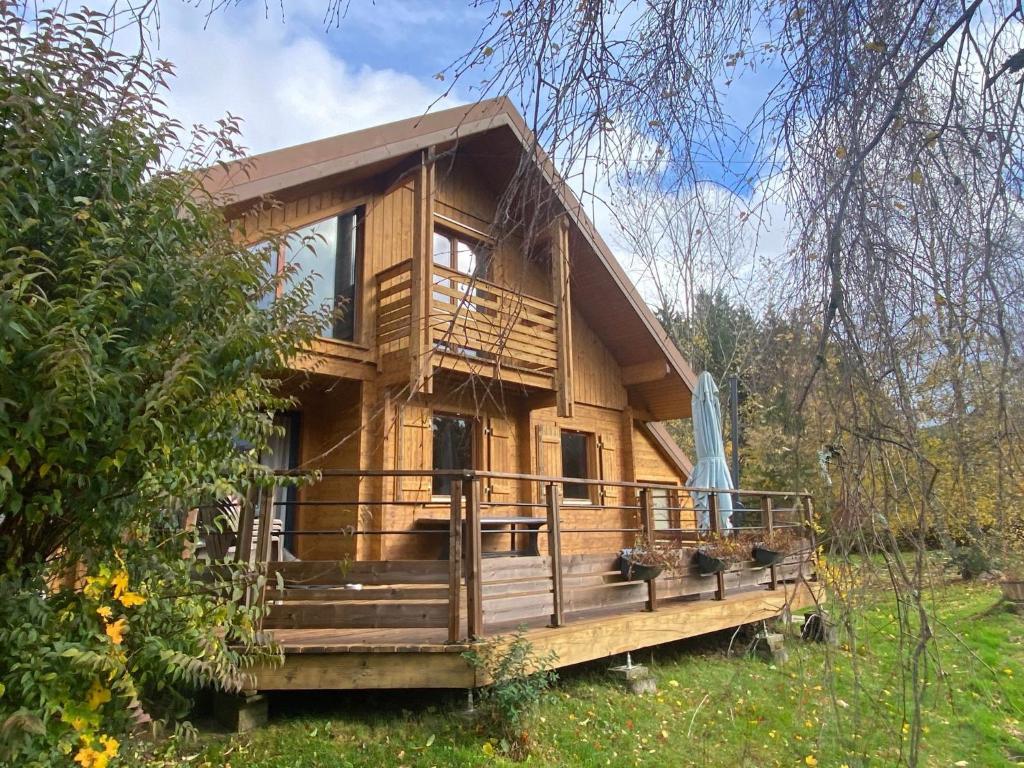 a log cabin with a large deck in the woods at Le chalet des Broches - jacuzzi in Xonrupt-Longemer