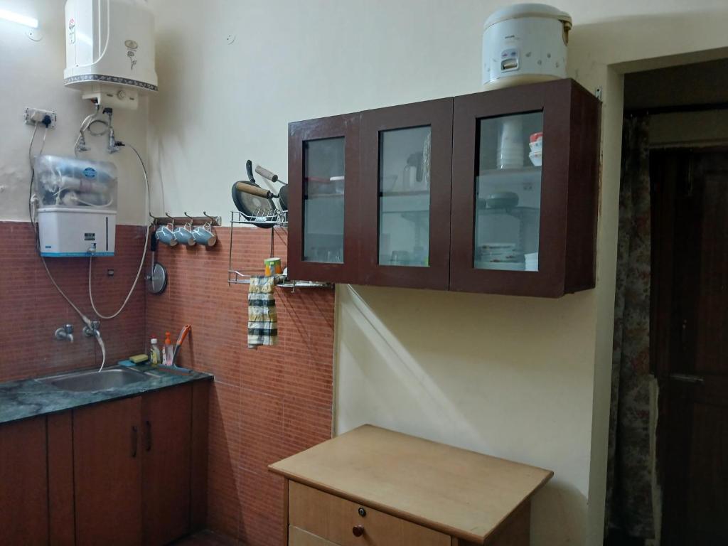 a kitchen with a sink and a wooden cabinet at Gharonda in Dehradun