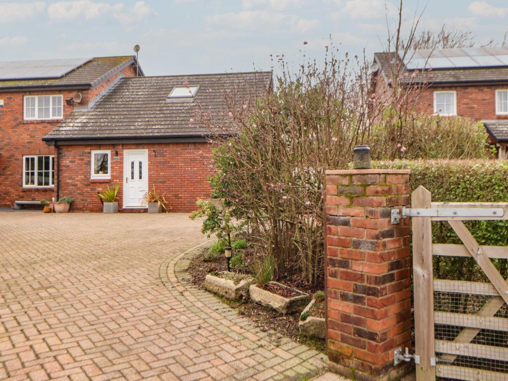 a brick house with a gate and a brick driveway at The Nook in Wigton