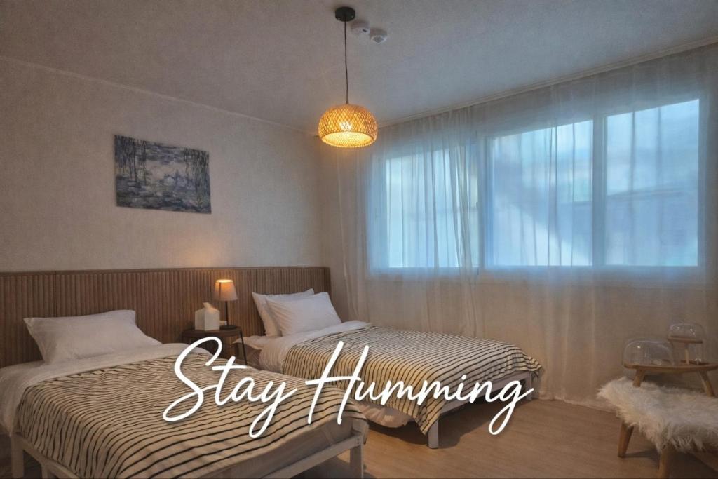 a bedroom with a bed and a window with the words stay humming at STAY Humming in Seoul