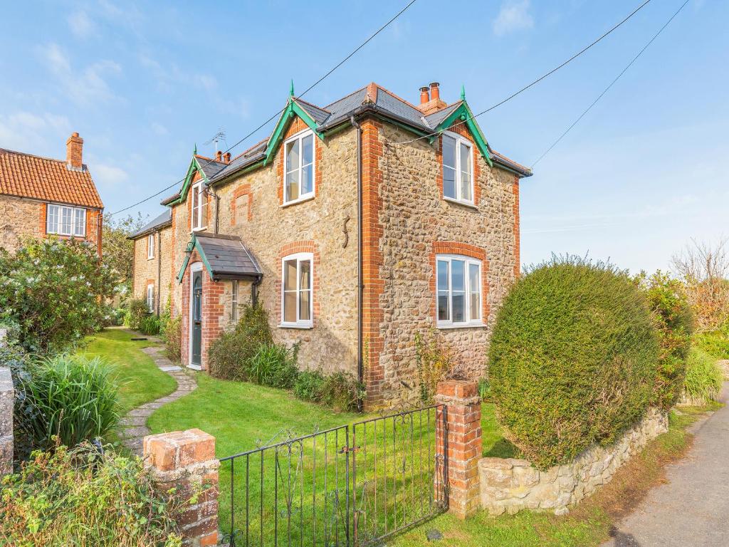 a brick house with a fence in front of it at Prosperous Villa in Puncknowle