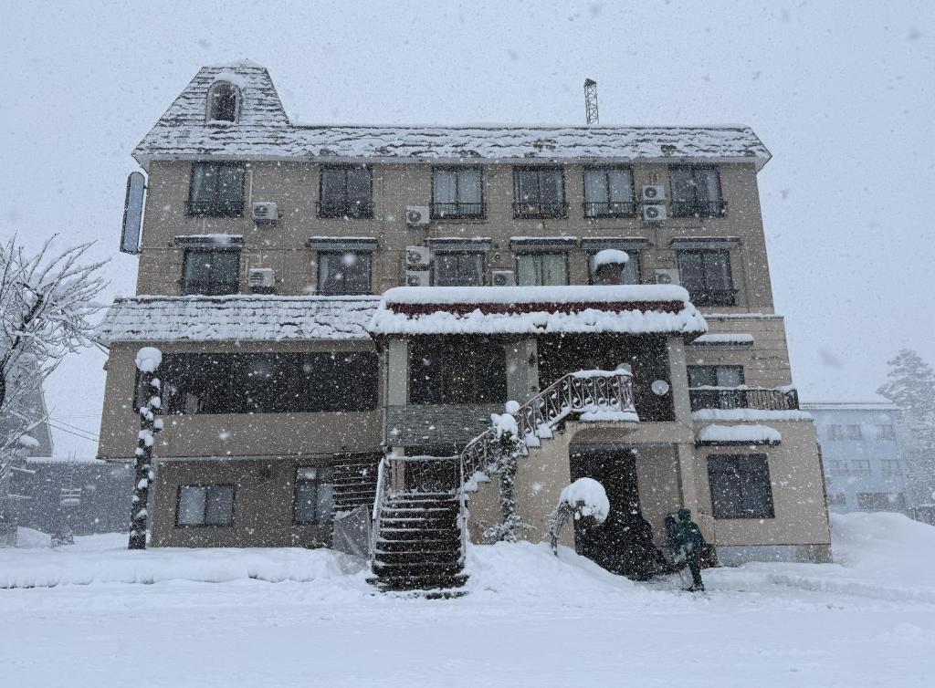 a building covered in snow in front of a building at Yuzawa Hotel New Fukudaya-ski in ski out in Minami Uonuma