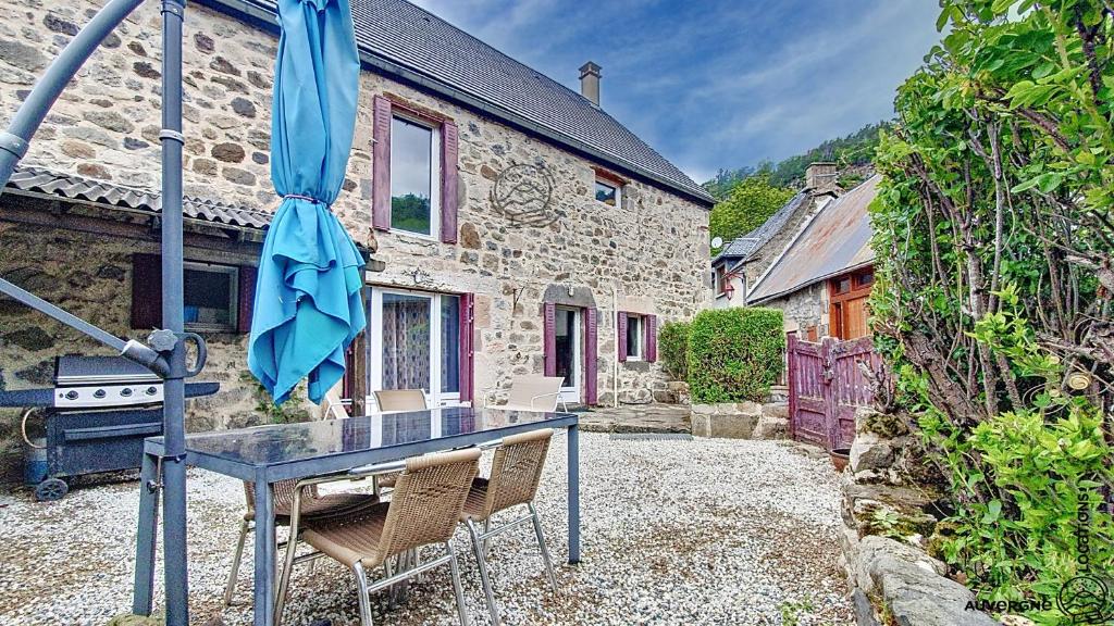 a table with chairs and an umbrella in front of a building at La Ferrandaise in Chambon-sur-Lac