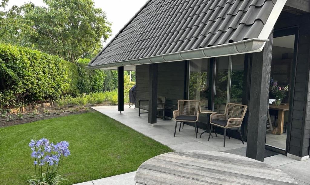 a patio with chairs and a table in a yard at Erve t Hoolterhof in Holten