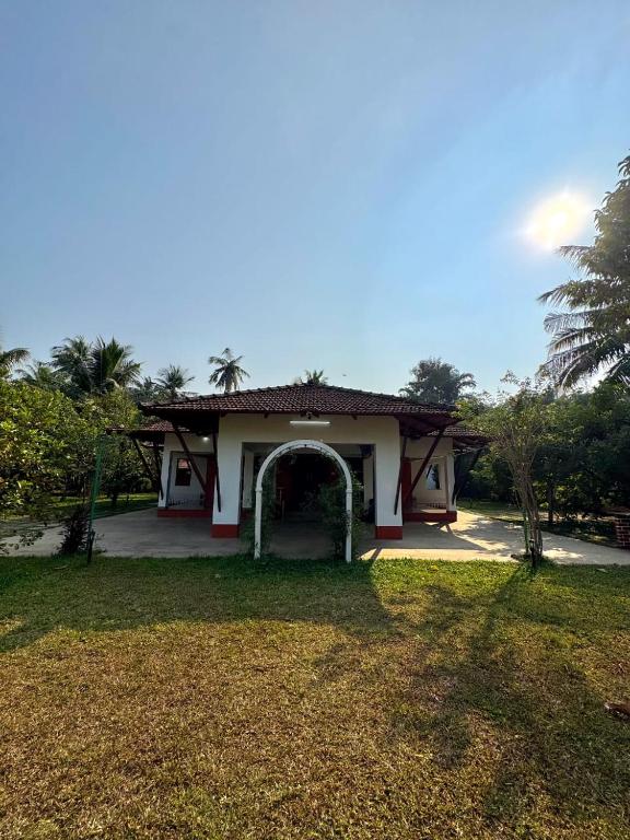 a small house with an arch in the yard at Rego Farms in Mangalore
