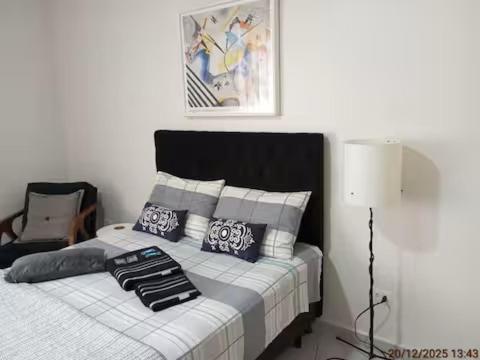 a bedroom with a bed with pillows and a lamp at Studio 215 Campinas SP in Campinas