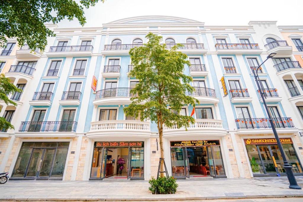 a large white building with a tree in front of it at Hotel Hải Âu in Sầm Sơn