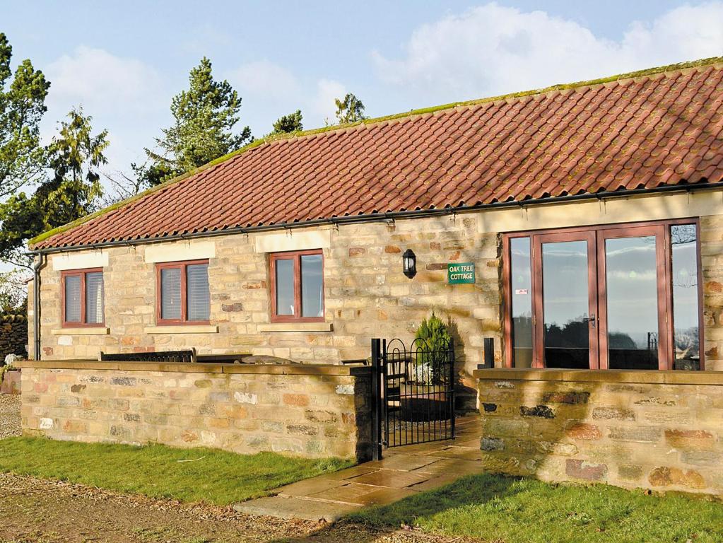 a small stone house with a red roof at Oak Tree Cottage in Kirkbymoorside