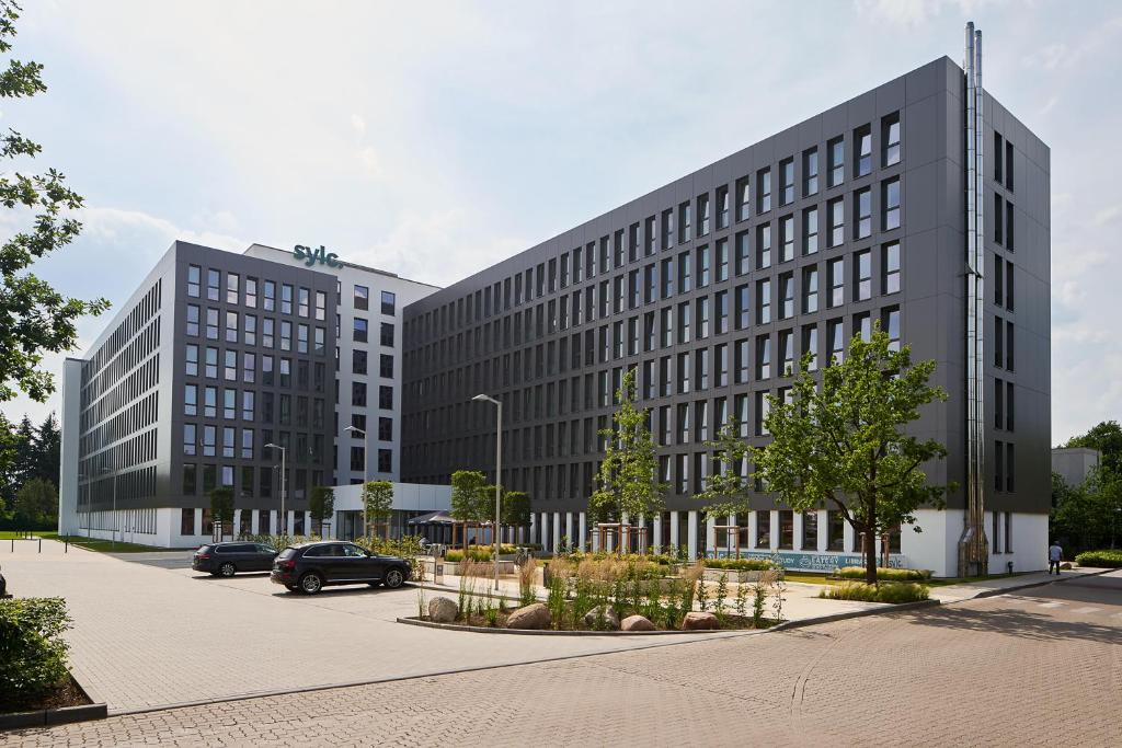 a large gray building with cars parked in a parking lot at sylc. Apartmenthotel – Serviced Apartments in Hamburg