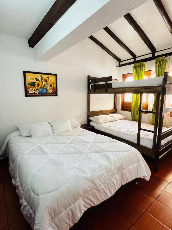 two beds in a room with two bunk beds at Hospedería Villa Lucía in Villa de Leyva