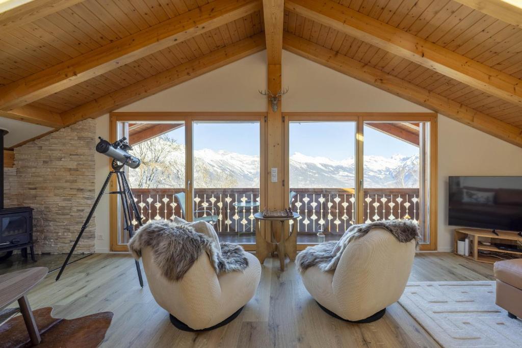 two chairs in a living room with a view of mountains at Chalet Nid Blanc in Nendaz