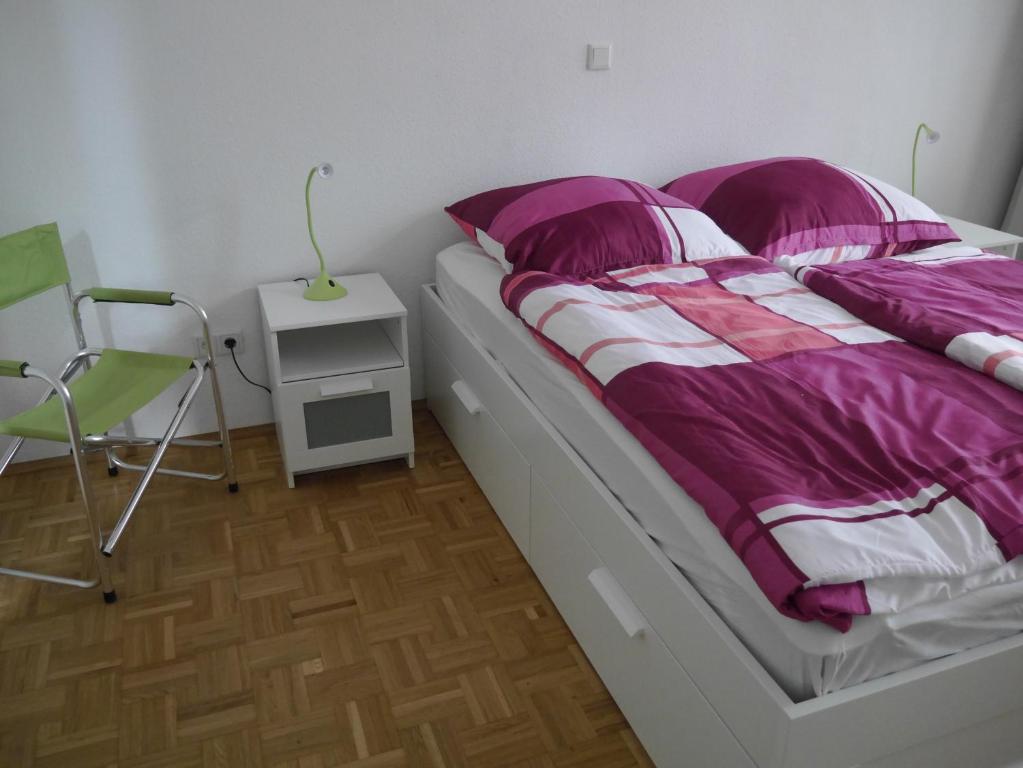 a bed with purple and white sheets and a side table at Schöne Ferien und Messewohnung Nähe Düsseldorf und Köln in Haan