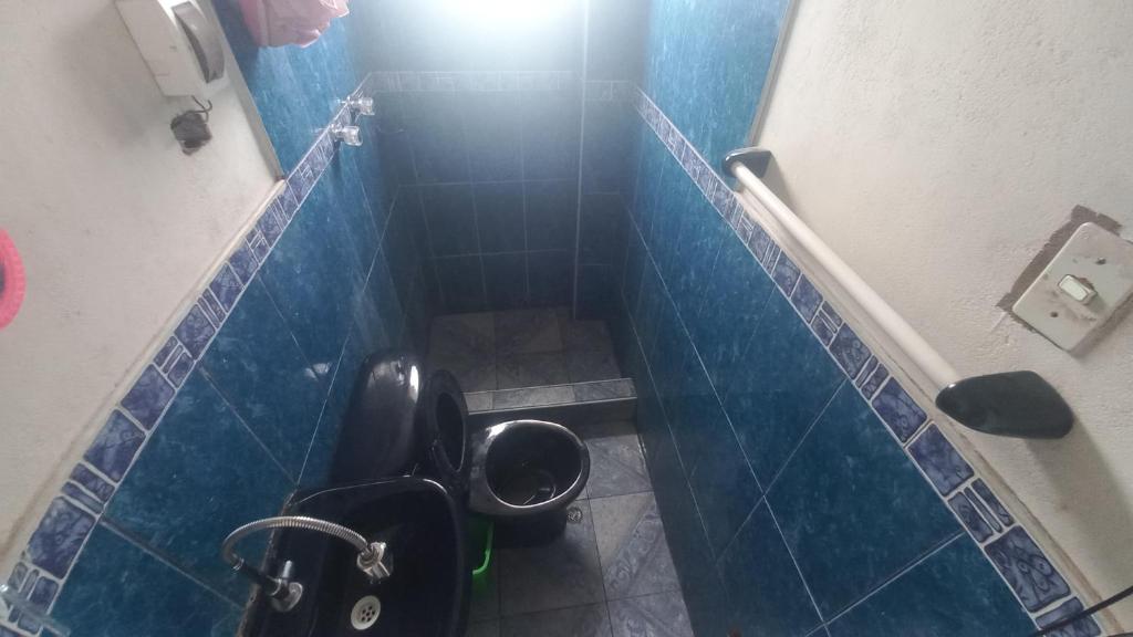 a bathroom with a toilet in a blue tiled stall at Cuarto por candelaria 2026 in Puno