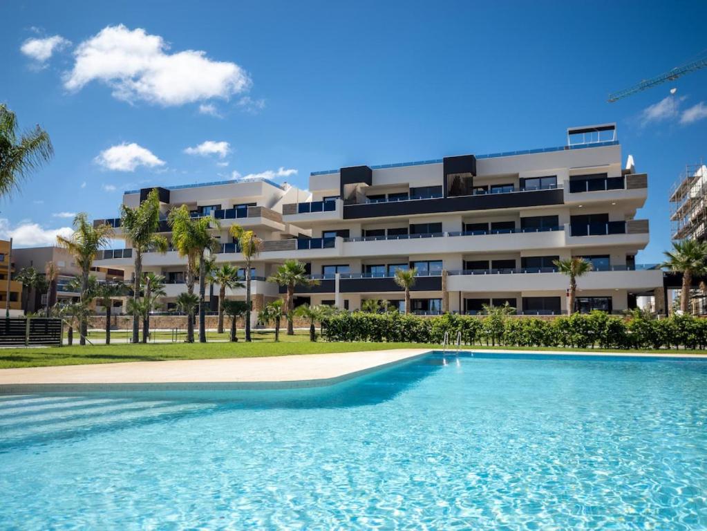 a swimming pool in front of a building at Playa Flamenca modern groundfloor apartment with pool access in Orihuela Costa