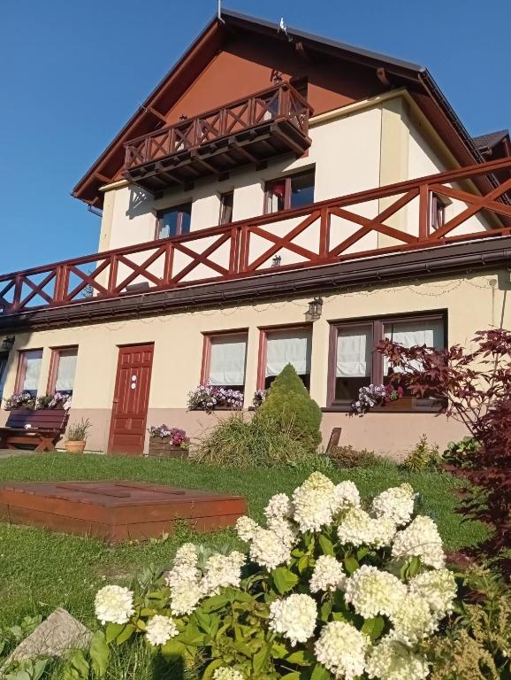 a house with white flowers in front of it at Pensjonat Halny Jaworzynka in Jaworzynka