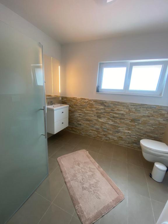 a bathroom with a toilet and a sink and a window at Ruhige Gästehaus AVOLli in Mellach