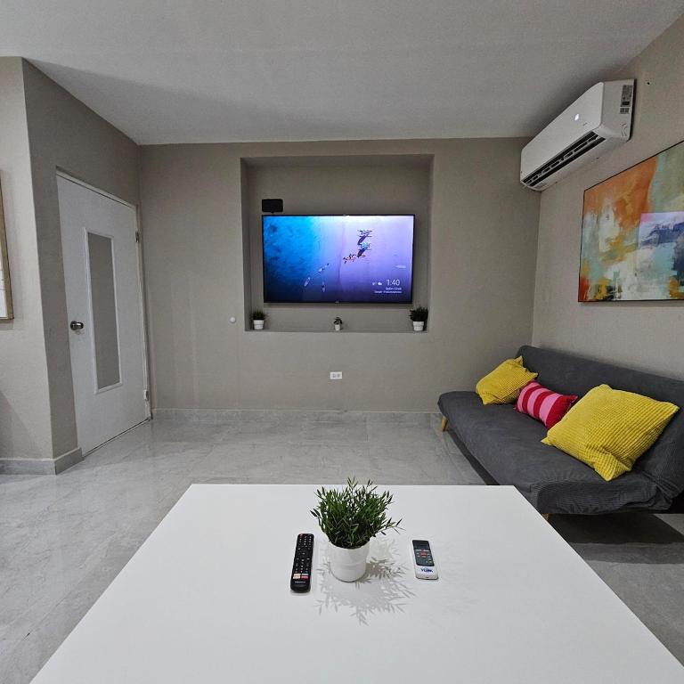 a living room with a couch and a tv on the wall at Latitude Adjustment in San Juan