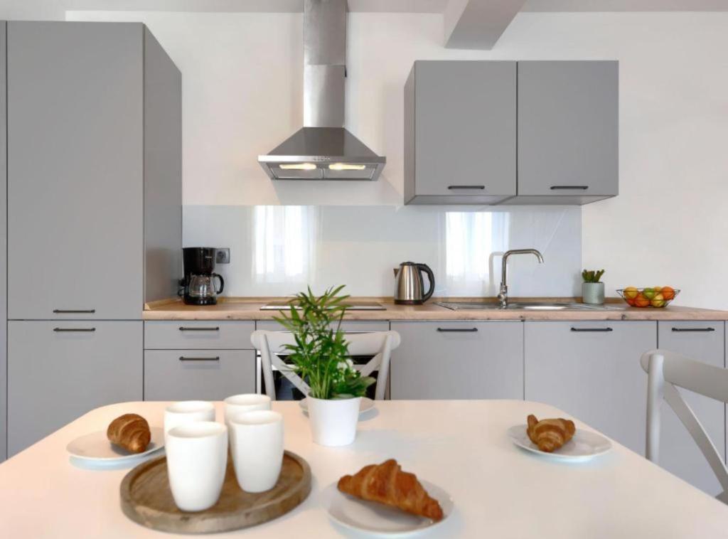 a white kitchen with a table with croissants and bread at Apartments Zanet & Niccolo in Fažana