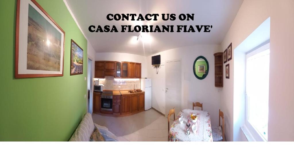 a living room with a green wall and a kitchen at Casa Floriani Fiavè-Comano Terme green in Fiavè