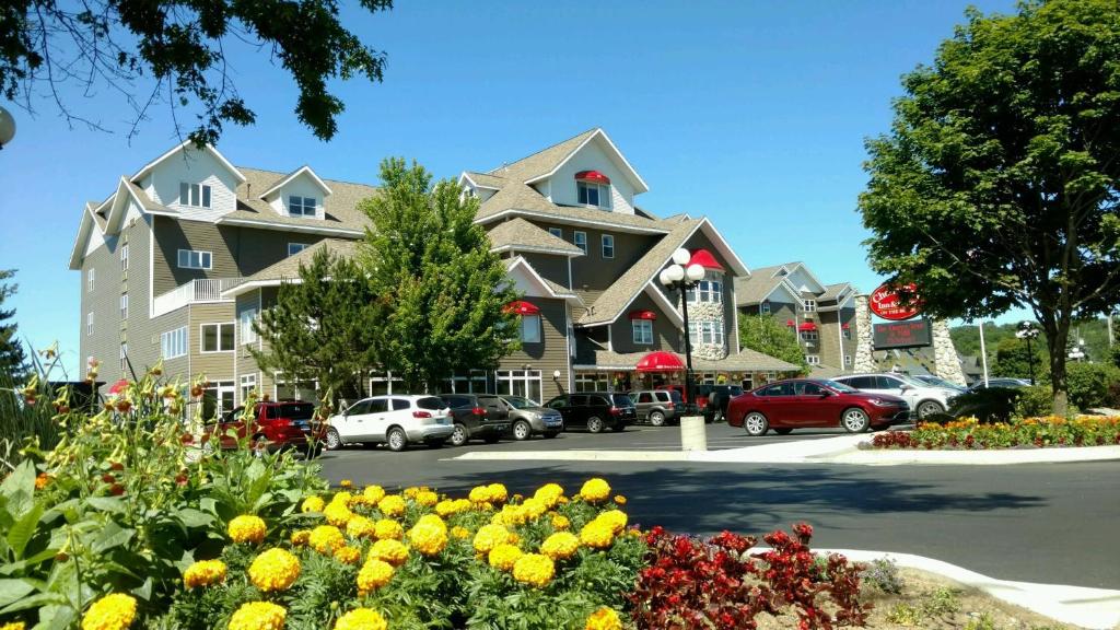 ein großes Gebäude mit Autos auf einem Parkplatz in der Unterkunft Cherry Tree Inn & Suites in Traverse City