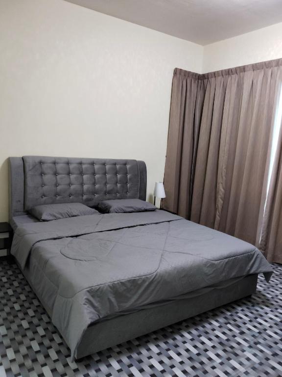 a bedroom with a large bed with a gray headboard at IJM Condostay, Sandakan in Sandakan