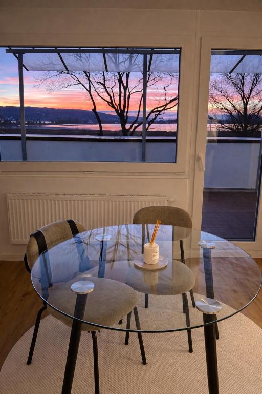 a glass table with two chairs and a table with a candle at Seeblick-Apartment am Bodensee bei Konstanz mit großer Terrasse in Reichenau