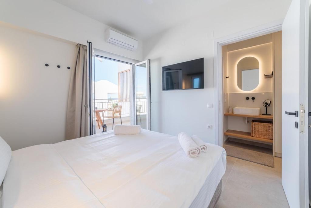 a white bedroom with a large bed and a balcony at Elia serenity apartment 4 in Mesochórion
