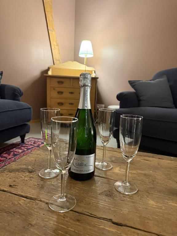 a bottle of wine and four empty wine glasses on a table at A l'Ancienne Ferme in Steinseltz